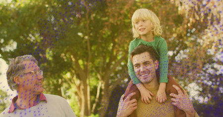 Walking adult male carrying blond child on shoulders, moving through park with mustard sweater....