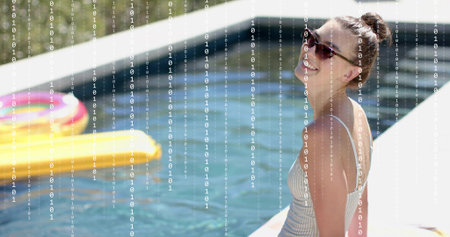 Sitting woman striped swimsuit wearing shades on white edge, yellow float, copy space. Poolside,...