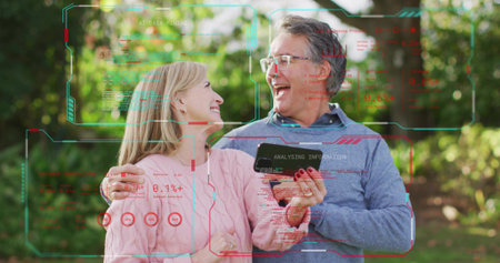 Laughing bespectacled man and ringed woman holding smartphone in sunlit garden with HUD, sweaters....