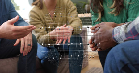 Gesturing group discussing in living room wearing knit sweaters and jeans, showing wireframe globe. Lounge, casual, collaboration, augmented, reality, holographic, overlayの写真素材