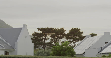 Showing two white gabled houses sitting in residential neighborhood, with metal roofs, solar panels....