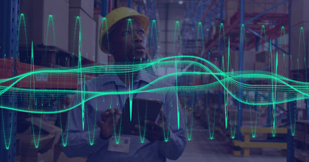 Holding tablet, worker in depot wearing yellow hard hat, ID badge checking racks with teal waveform. Warehouse, logistics, teamwork, automation, efficiency, analytics, industrialの写真素材