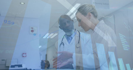 Reviewing clinicians in white coats pointing at tablet at nursing station counter with stethoscope. Hospital, medical, doctors, teamwork, collaboration, digital, overlayの写真素材