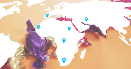 Displaying white map cutout centered on orange tabletop, showing blue pins and purple gold wrappers....