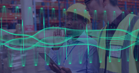 Viewing two warehouse staff checking tablet and sensor waveform overlay in aisle, helmets, vests. Industrial, logistics, fulfillment, collaboration, teamwork, analytics, liveの写真素材