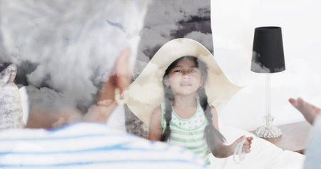 Sitting girl wearing striped top and straw hat holding beads in bedroom, lamp showing clouds. Family, child, bed, cozy, intimate, dreamlike, doubleexposureの写真素材