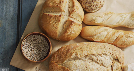 Displaying round boule, baguette, seeded roll on painted blue table with wooden bowl of seeds....