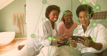Leaning three women sharing touchscreen device in bedroom loft with finance icon overlay. Trio,...