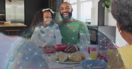 Laughing mid adult man and child girl sharing breakfast at home kitchen table, with network overlay. Multigenerational, family, dining, candid, warmth, joy, modernの写真素材
