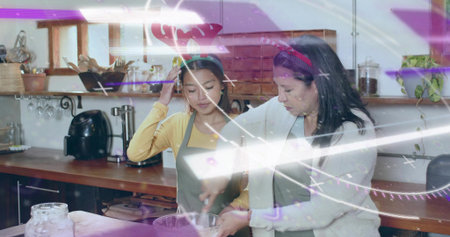 Stirring two women wearing headbands and aprons preparing food in home kitchen, glass mixing bowl. Pair, warmth, rustic, wooden, shelves, jars, plantsの写真素材