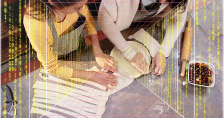 Shaping family duo wearing aprons, mustard top, light sweater pressing dough on counter. Pastry,...