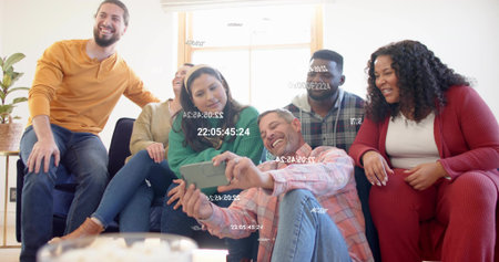 Taking selfie of six adults leaning on living room couch near table, holding phone with overlays. Group, casual, candid, smiling, interior, sofa, brightの写真素材