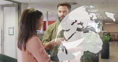 Explaining bearded man holding papers and pink blazer woman holding tablet in office, globe overlay....