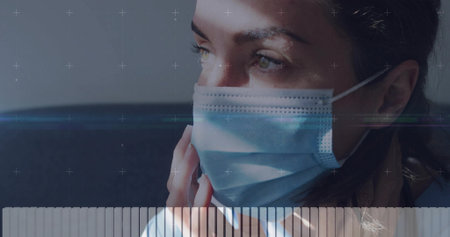 Touching adult woman adjusting disposable blue mask at home, with hand, sofa and graphic overlays. Facecovering, portrait, lensflare, interior, livingroom, serene, minimalistの写真素材