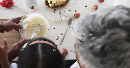 Whisking family trio at home kitchen, man long-sleeve, child pink headband, mixing bowl and eggs....