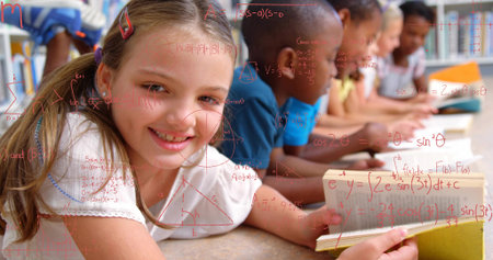 Reading smiling girl holding open book on school carpet, others studying red formulas, copy space....