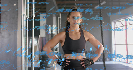 Standing athlete placing hands on hips at gym, in black sportswear. Fitness, woman, competitor,...