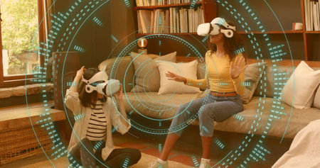 Gesturing two women wearing white VR headsets, interacting with teal holographic HUD in living room....