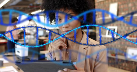 Reading woman in beige blazer touching chin while holding tablet in open office. Workspace, collaboration, focus, modern, brick, monitors, deviceの写真素材