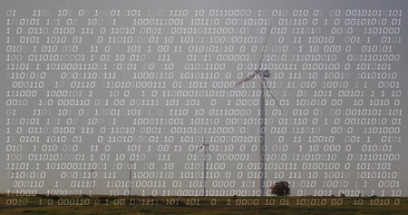 Standing tall wind turbine towering grassland near shrubs, with copy space. Tower, rural, landscape, field, overcast, cloudyの写真素材