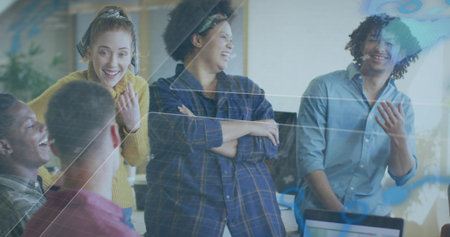 Laughing six casual coworkers discussing at office desk with laptop and reflective glass overlay....