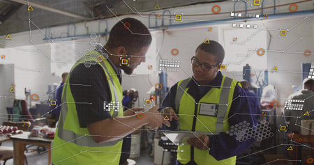 Pointing, two workers in neon-yellow vests reviewing tablet at workshop, with overlay graphics....