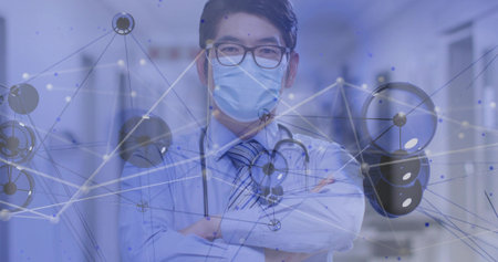 Standing doctor arms-crossed in hospital, wearing striped-tie, stethoscope, mask with data overlay. Clinician, corridor, clinic, glasses, blue, digital, graphicsの写真素材