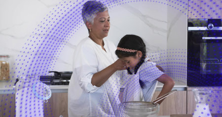 Wiping mature man white-shirt guiding child in apron at kitchen, mixing bowl, whisk, purple overlay. Caregiver, parent, kid, bonding, learning, cooking, familyの写真素材