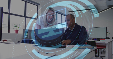 Collaborating pair leaning over laptop, typing in office, wearing office attire, showing AR overlay....