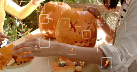 Carving two women in striped shirt and pale longsleeve on patio, carving jack-o'-lanterns, AR icons. Pumpkin, collaboration, autumn, outdoor, sunlit, backyard, rusticの写真素材