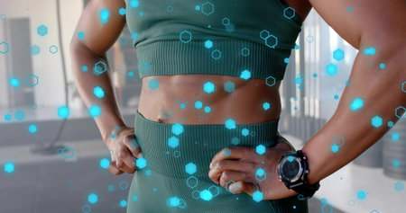 Standing woman wearing green ribbed set, black sports watch at gym, showing blue hex AR overlay. Athletic, fitness, workout, strength, toned, torso, activewearの写真素材