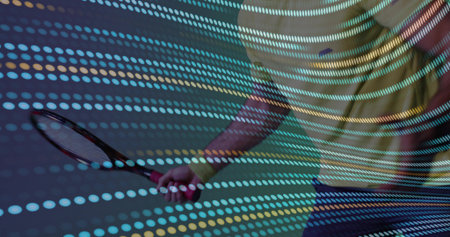 Holding tennis racket, male torso wearing yellow tee and dark shorts in studio with dotted lights....
