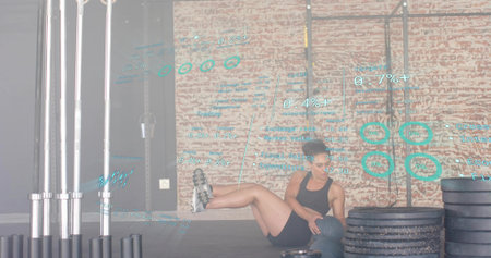 Performing female exerciser holding medicine ball reclining on mat in gym, wearing black gear. Athlete, strength, fitness, weights, barbell, plates, studioの写真素材