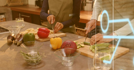 Chopping two women in aprons preparing vegetables on kitchen counter, with knives. Produce, peppers,...