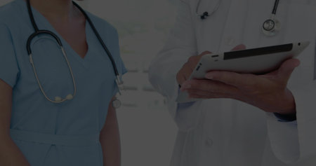 Reading two clinic staff consulting on tablet in clinic, showing stethoscopes lab coat and scrubs. Hospital, colleagues, collaboration, healthcare, device, stylus, modernの写真素材