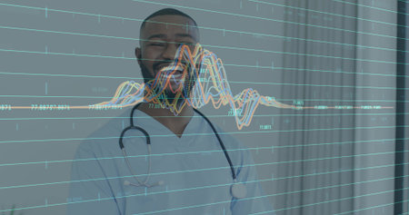Smiling doctor wearing light blue scrubs and stethoscope standing in clinic, with waveform overlay. Healthcare, medicine, clinical, analytics, data, visualization, professionalの写真素材