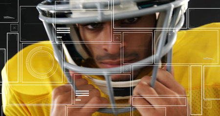 Gripping facemask football player adjusting chinstrap in studio with yellow jersey overlays. Helmet, headshot, focus, intensity, uniform, pads, goldの写真素材