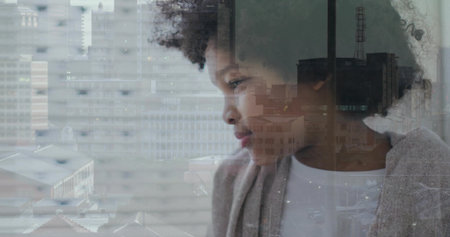 Gazing boy wearing white shirt, light-gray cardigan at home by window, reflecting roofs, copy space. Portrait, child, urban, cityscape, glass, overlay, contemplativeの写真素材