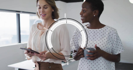 Holding tablet and gray mug, two women wearing blouses discussing data near window with HUD overlay. Collaboration, teamwork, professional, modern, minimalist, openplan, urbanの写真素材