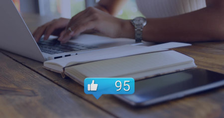 Typing female hands in ribbed top on wooden cafe table with laptop notebook tablet alert bubble. Coworking, productivity, sunlit, greenery, focus, modern, bokehの写真素材