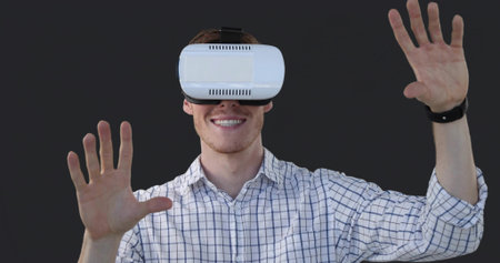 Smiling man wearing checked shirt in studio reaching interacting with white headset, dark wristband....