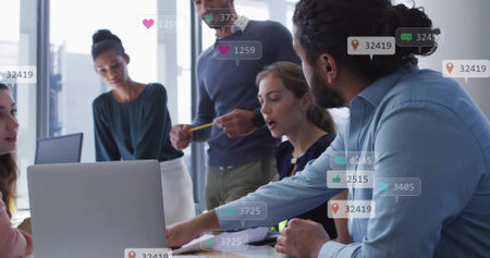 Discussing 5-person team in shirts pointing at laptop papers pencil in office with social icons. Collaboration, professionals, brainstorming, documents, analytics, insights, urbanの写真素材