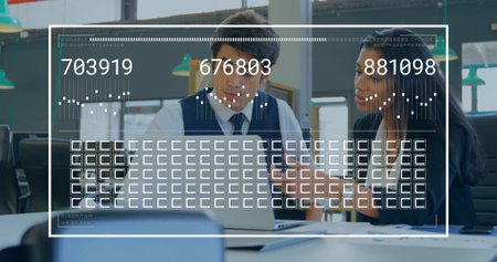 Collaborating two colleagues in business attire studying laptop at open-plan office desk, with HUD. Teamwork, collaboration, computer, dashboard, analytics, graphs, workspaceの写真素材