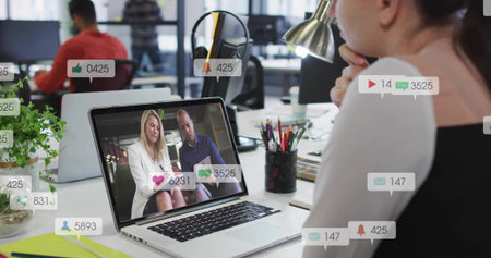 Watching woman in business attire at office desk viewing laptop with social icons, copy space....