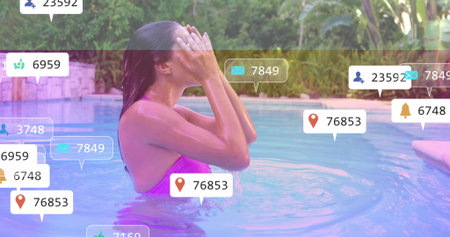 Splashing woman in pink swimsuit rinsing face while standing in backyard pool with icons. Swimwear,...