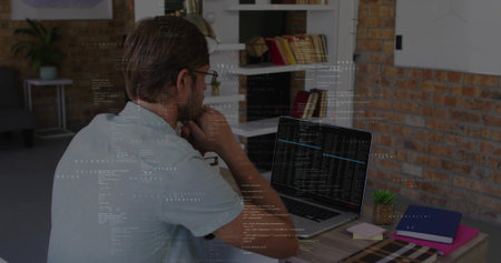 Studying mid-adult man analyzing code on laptop at home office, with shelving succulent notebooks....