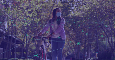 Holding bicycle, woman wearing purple jacket, jeans and blue surgical mask on path, with AR overlay. Cycling, urban, augmented, reality, sunlit, calm, commuterの写真素材