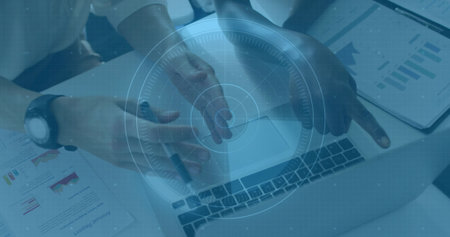 Pointing and gesturing with two colleagues' hands wearing long sleeves over laptop at desk, charts. Collaboration, teamwork, analytics, graphs, reports, office, technologyの写真素材