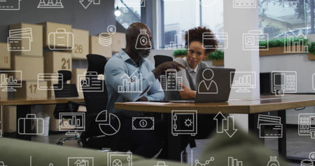 Pointing man in light blue shirt, woman in gray sweater, reviewing laptop data in modern office. Collaboration, analytics, meeting, workspace, openplan, focus, greeneryの写真素材