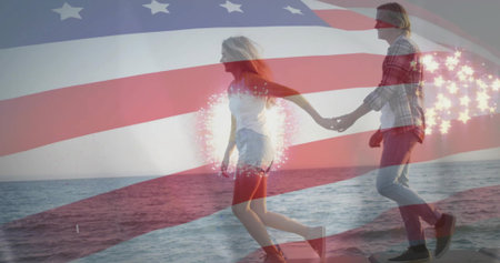 Strolling couple holding hands on rocky shore, sparkling overlay near hands, in casual wear. Romance, silhouette, backlit, seascape, horizon, dawn, serenityの写真素材